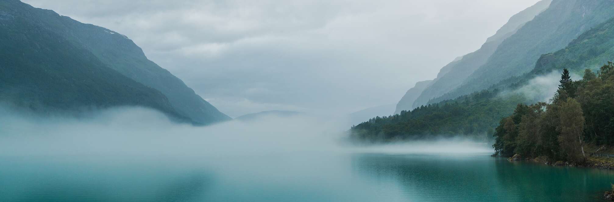 Tåke som stiger opp fra fjorden og avdekker et fredelig og gåtefullt landskap