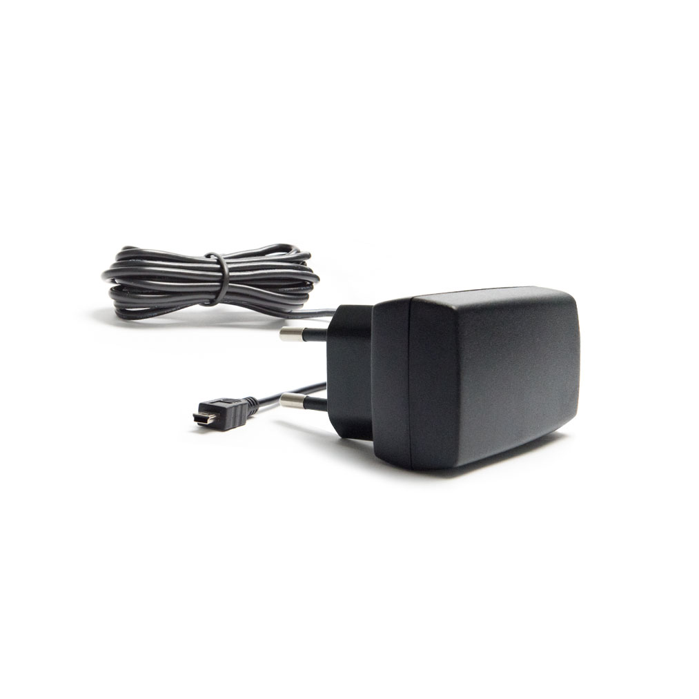 Svart vegglader med to runde plugger og tilkoblet kabel, liggende ved siden av en sammenrullet ledning på hvit bakgrunn.