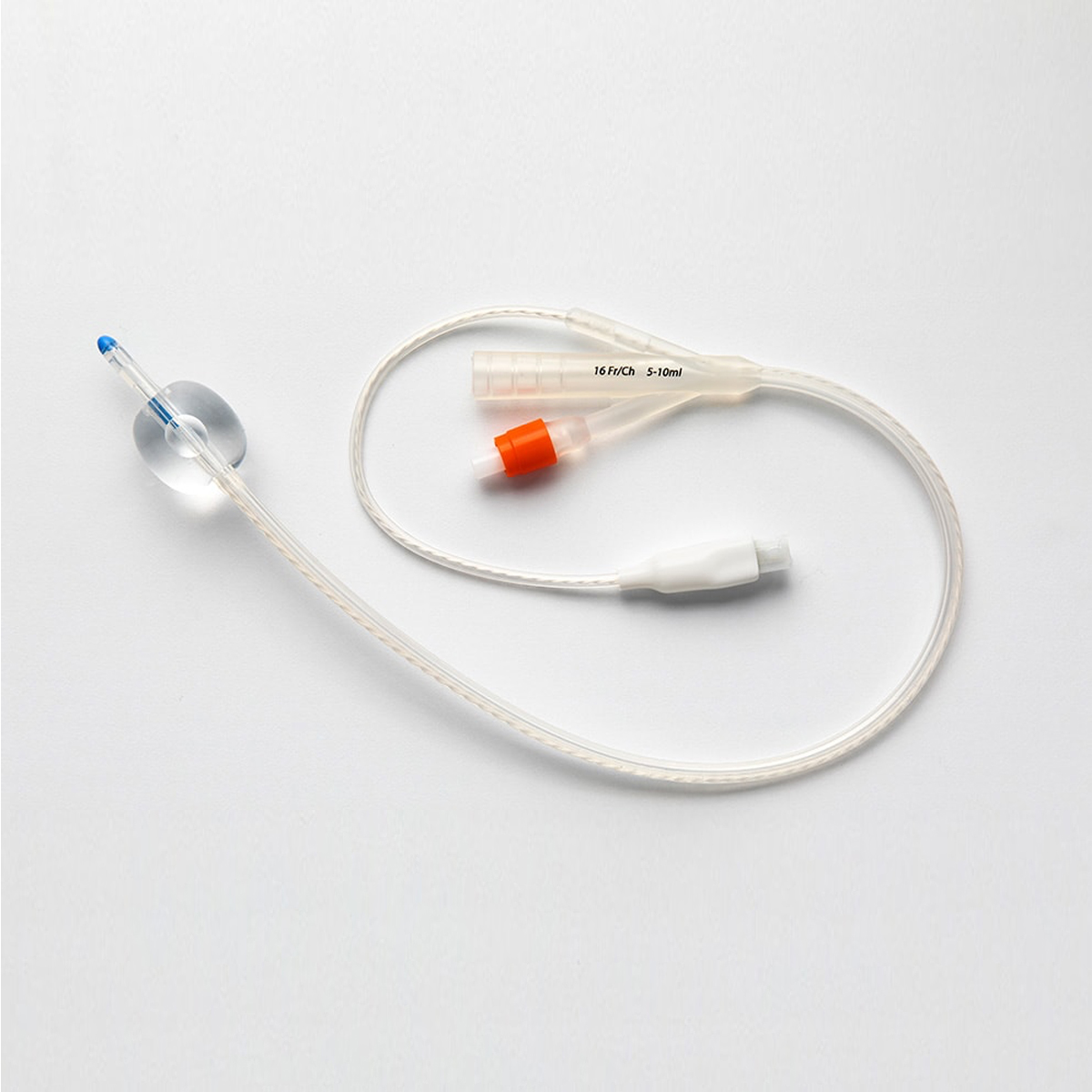 En urinkateter av plast med ballong og to innløp, ligger på en hvit overflate.