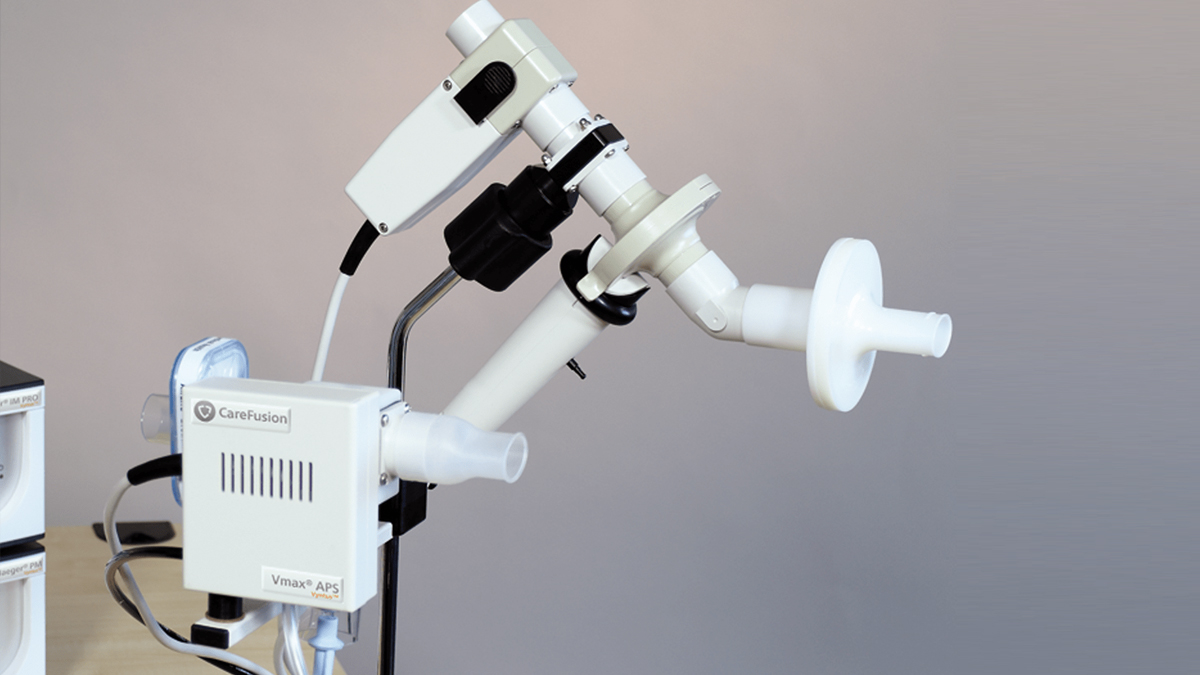 Apparat for spirometri med hvite og grå komponenter på en lys bakgrunn.