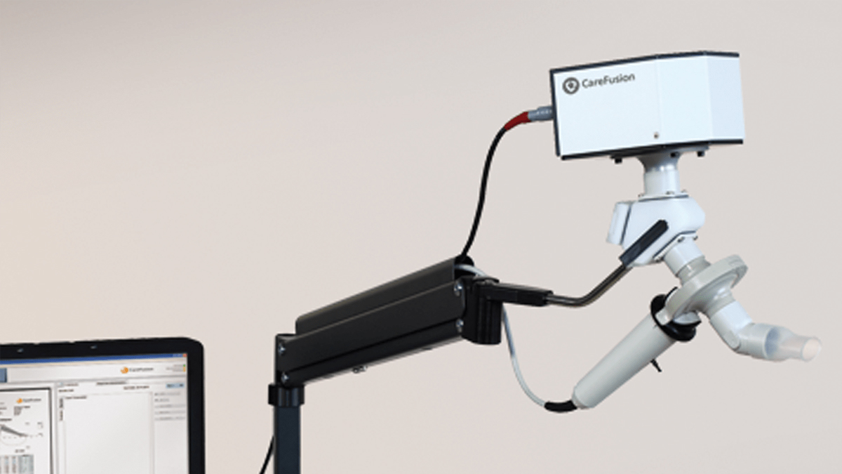 Medisinsk spirometermaskin med munnstykke og tilkoblet dataskjerm, brukt til å måle lungefunksjon.