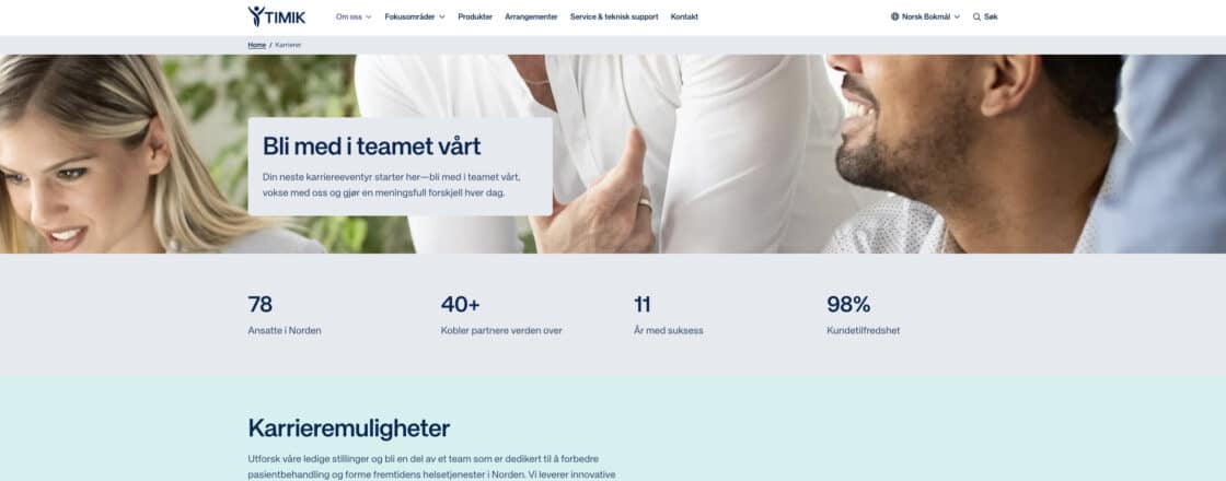 To personer smiler og samarbeider på en lys, moderne arbeidsplass. Tekst: "Bli med i teamet vårt".